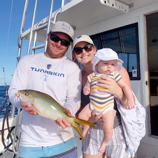 Captain James holding a Yellowtail Snapper with his wife, Annie, and son, Benjamin.
